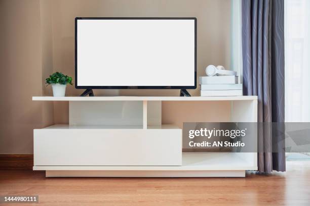 smart tv on the cabinet in modern living room on white wall background. modern white shelf with flat tv at home - soporte-de-televisión fotografías e imágenes de stock
