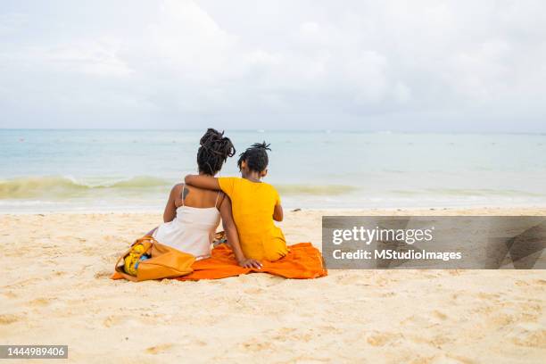 mutter und tochter sitzen am strand und beobachten die wellen - playa del carmen stock-fotos und bilder