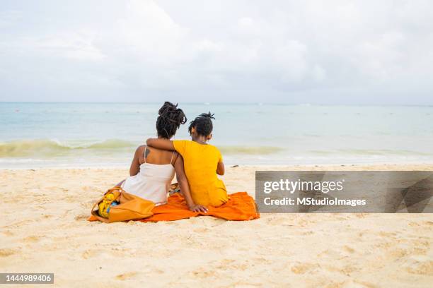 mère et fille s’assoient sur la plage et regardent les vagues - playa del carmen photos et images de collection