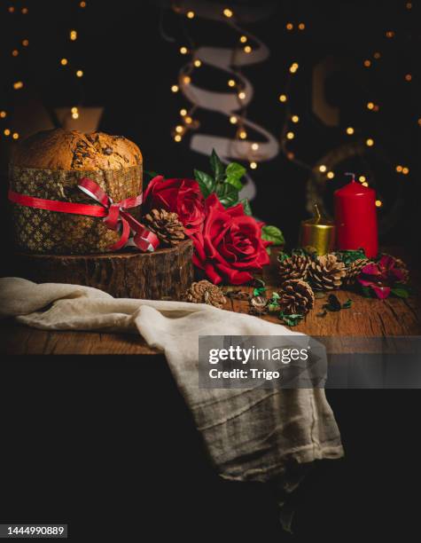 weihnachtstischfoto, mit kerzen und panettone und roten blumen, auf einem hintergrund mit unscharfen lichtern und kopierraum. - süßes brot stock-fotos und bilder