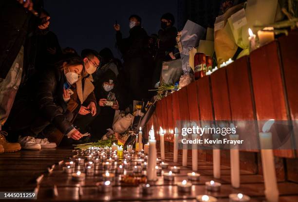 Protesters light candles and leave cigarettes at a memorial during a protest against Chinas strict zero COVID measures on November 27, 2022 in...