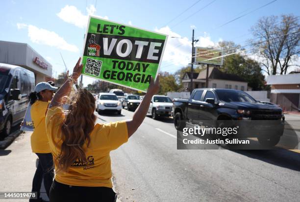 Volunteers hold signs to encourage people to early vote outside of a polling station on November 27, 2022 in Atlanta, Georgia. Early voting has...