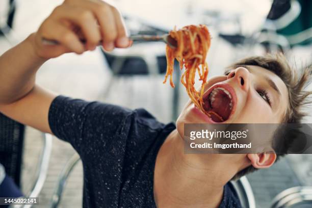 teenage boy enjoying eating spaghetti very much. - child mouth open stock pictures, royalty-free photos & images