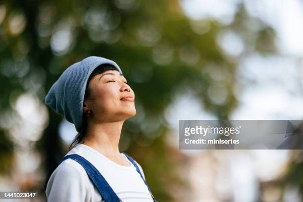 smiling woman enjoying fresh air in the city park - fresh air breathing stockfoto's en -beelden