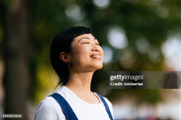 femme souriante profitant de l’air frais dans le parc de la ville - woman fresh air photos et images de collection
