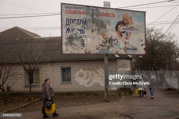 People walk past a destroyed Russian billboard on November 26, 2022 in Kherson, Ukraine. Ukrainian forces took control of Kherson, as well as swaths...