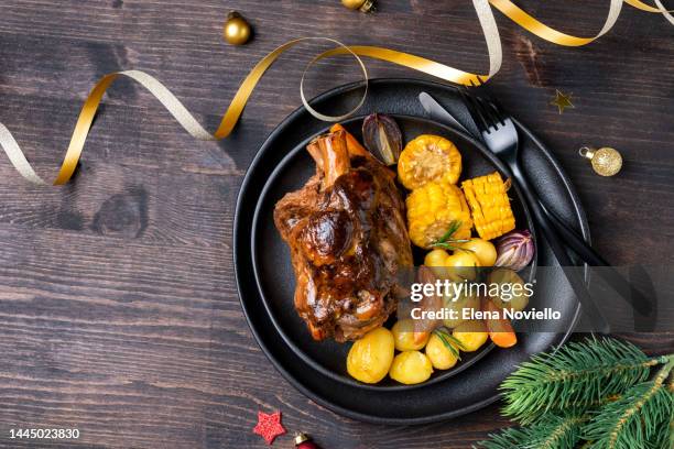 pork shank knuckle with baked potatoes and corn, dinner food christmas new year - christmas leg ham photos et images de collection