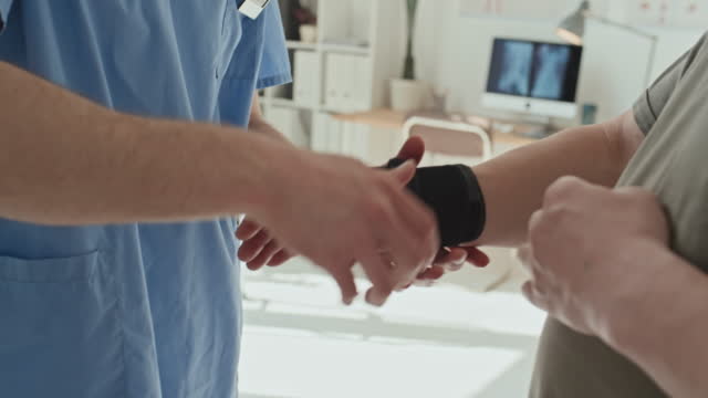 Doctor Wearing Tapes on Injured Hand of Patient