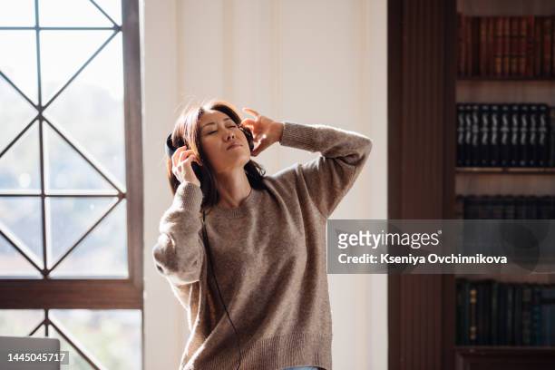 full length of young happy lady packing luggage in bedroom relax in day time. joyful girl listening to music with headphones holding mobile phone dancing having fun in leisure time home real moment - bedroom radio stockfoto's en -beelden