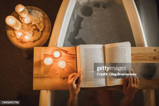 woman reading book in bath. cozy and romantic evening with candles, self-care and relaxation - candle overhead stock pictures, royalty-free photos & images