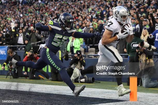 Foster Moreau of the Las Vegas Raiders scores a touchdown past Jordyn Brooks of the Seattle Seahawks in the fourth quarter at Lumen Field on November...
