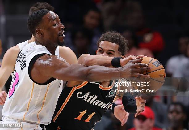 Trae Young of the Atlanta Hawks is defended by Bam Adebayo of the Miami Heat during the first half at State Farm Arena on November 27, 2022 in...