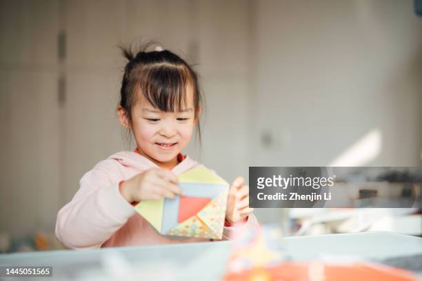 4 years girl learning paper folding joyfully - origami spiel stock-fotos und bilder