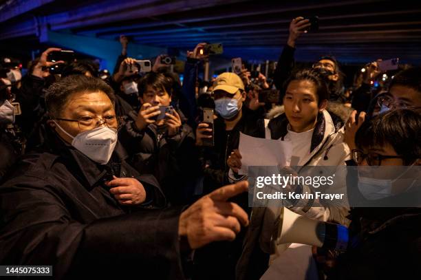 Government official at left speaks to participants in a protest against China's strict zero COVID measures on November 28, 2022 in Beijing, China....