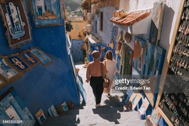 rear view 2 asian chinese female tourist shopping in souk market in chefchaouen - chefchaouen medina stock pictures, royalty-free photos & images