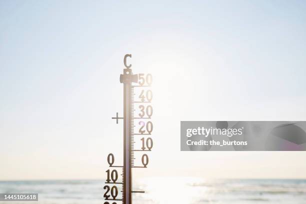 thermometer against sea, sky and sun - celsius stock-fotos und bilder