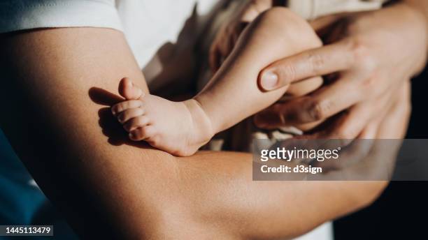 close up of a loving young asian father carrying his newborn baby daughter in arms. bonding moment of father and daughter. fatherhood. skin to skin contact. love, care and tenderness - babyhood - fotografias e filmes do acervo
