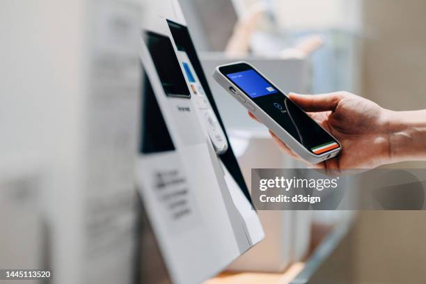 close up of a woman's hand making mobile payment with her smartphone in a shop, scan and pay a bill on a card machine making a quick and easy contactless payment at self checkout counter. nfc technology, tap and go concept - apple pay imagens e fotografias de stock