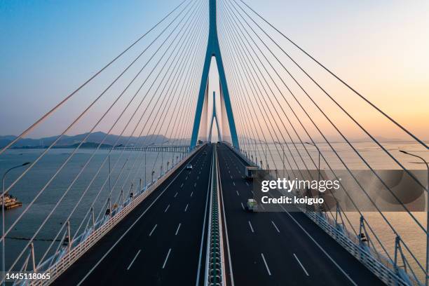 aerial photography of cross-sea highway at sunset - brücke stock-fotos und bilder
