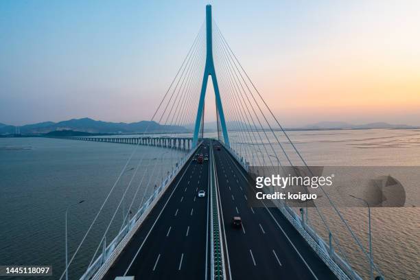aerial photography of cross-sea highway at sunset - hängebrücke stock-fotos und bilder