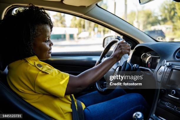 young woman cleaning the steering wheel in her car with antibacterial wet wipe - hand sanitizer in car stock pictures, royalty-free photos & images