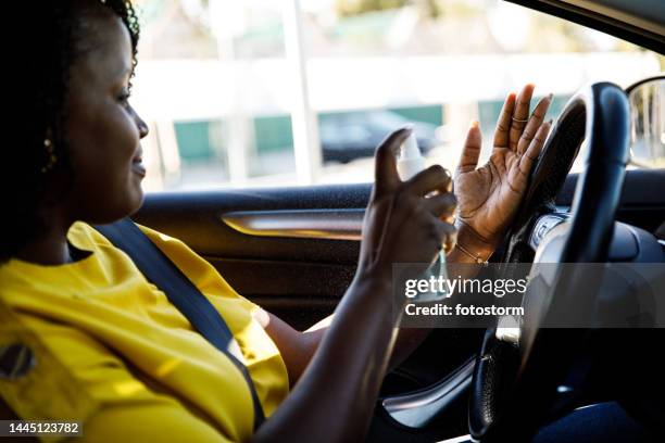 candid shot of young woman spraying disinfectant spray on her hands - hand sanitizer in car stock pictures, royalty-free photos & images