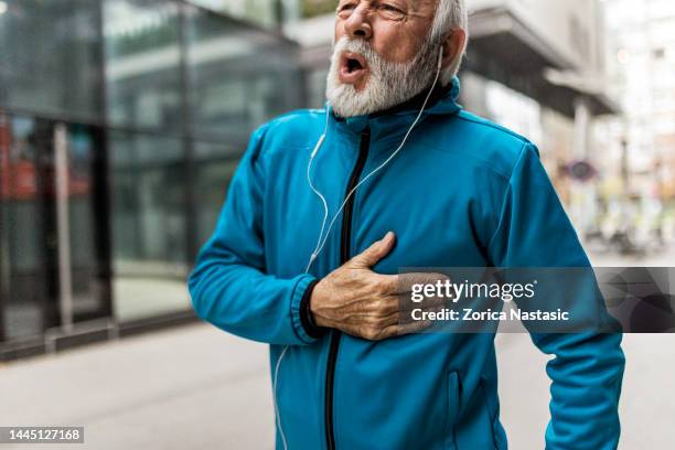 senior man having heart problems while jogging - missed train stockfoto's en -beelden