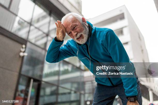 tired senior man jogging in city taking a break - center athlete stock pictures, royalty-free photos & images