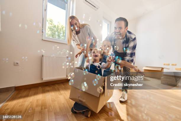 unbeschwerte familie, die spaß hat, nachdem sie in ein neues zuhause gezogen ist. - people inside bubbles stock-fotos und bilder