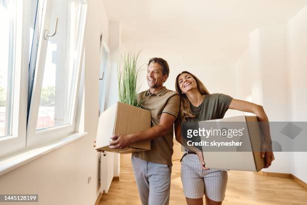 feliz pareja cargando cajas en su nuevo apartamento. - pareja de mediana edad fotografías e imágenes de stock
