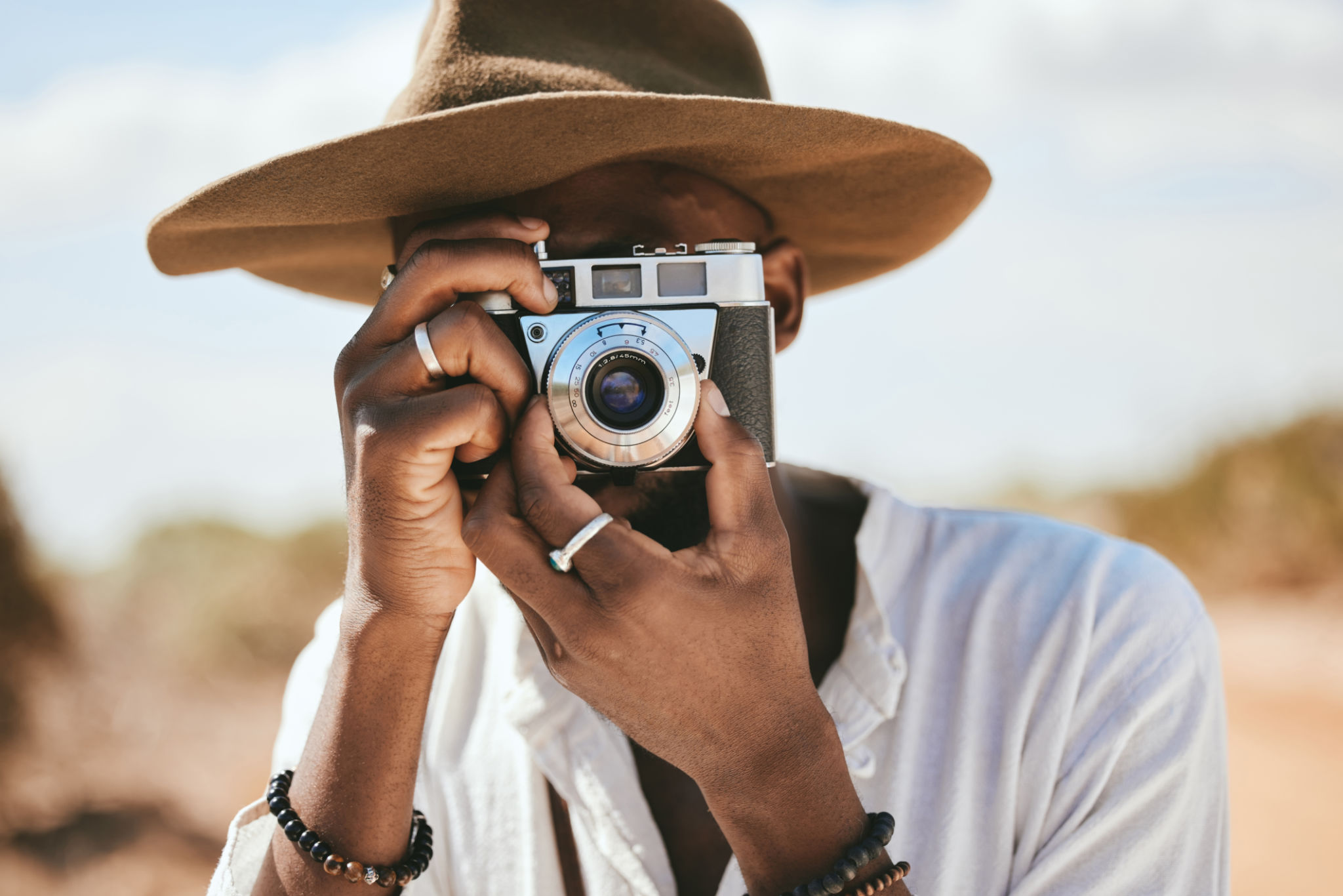 Tourist, photographer and black man with camera to take photograph or pictures during travel adventure in summer on nature vacation. Closeup of male on photography trip holiday outdoors in safari Tourist, photographer and black man with camera to take photograph or pictures during travel adventure in summer on nature vacation. Closeup of male on photography trip holiday outdoors in safari