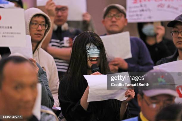 Protester covers face with mask and holds up white sign in protest on November 28, 2022 in Melbourne, Australia. Urumqi officials said 10 people were...