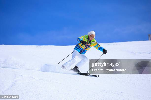 vital senior, gray-haired men snow skier skiing, enjoying on sunny ski resorts. skiing carving at high speed against blue sky. - senior winter sport stock pictures, royalty-free photos & images