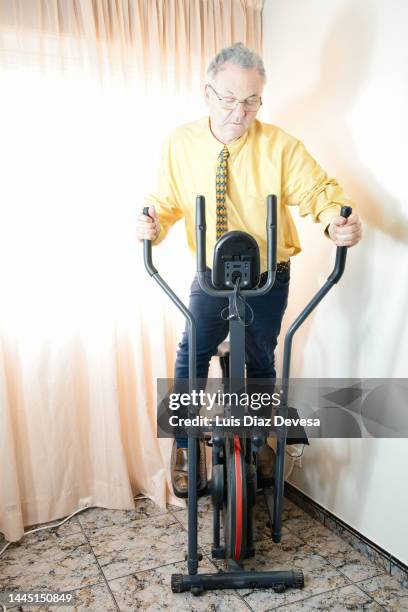 business man exercising on an elliptical bike. - cross trainer stock-fotos und bilder
