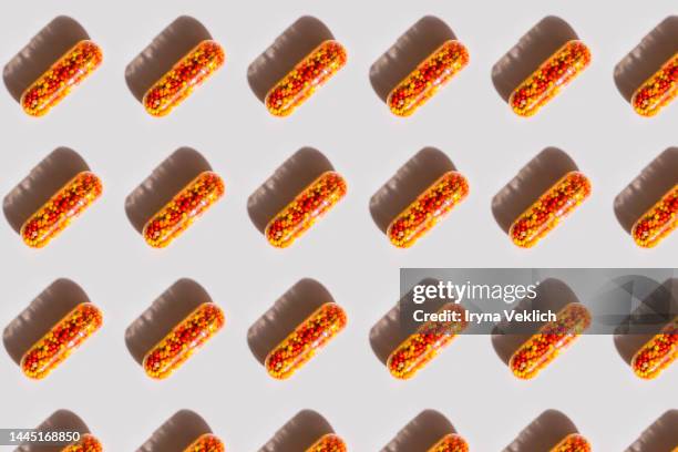 pattern made of  red-orange capsule with medicine  with iron, vitamin b, vitamin c, folic acid, zinc on a white background with shadow. - clear skin red background stock pictures, royalty-free photos & images