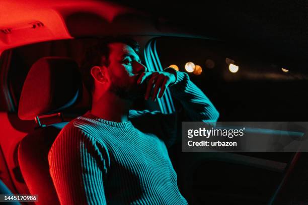 joven esperando en su auto por la noche - boredom man fotografías e imágenes de stock