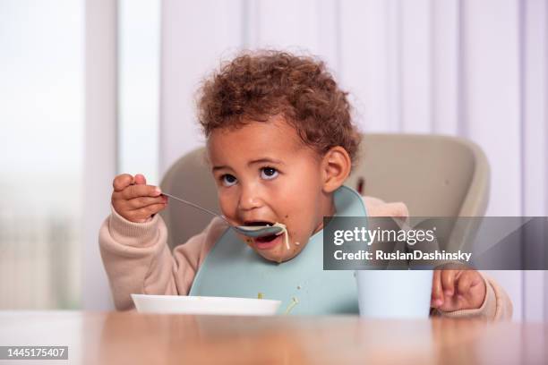 baby girl eating from a plate. - spoon in hand stock pictures, royalty-free photos & images