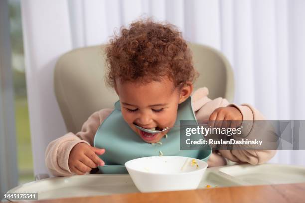 baby girl eating from a plate. - spoon in hand stock pictures, royalty-free photos & images