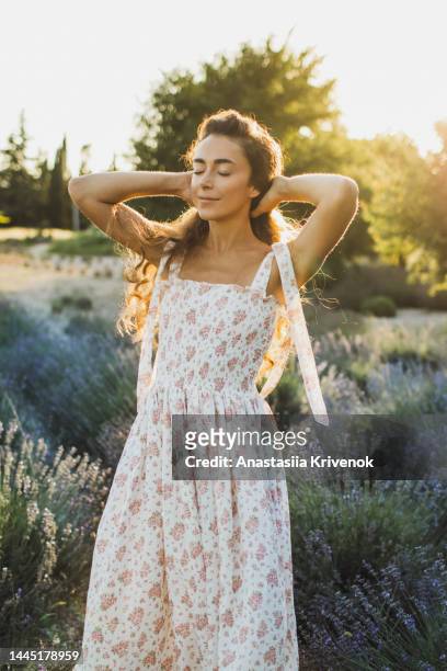 beautiful woman with long hair in dress walking outdoor through lavender field in summer. - flower blossom - fotografias e filmes do acervo