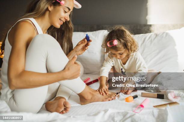 little daughter trying to make pedicure to her mother, want to be as adult. funny childhood. beauty and care - fußpflege stock-fotos und bilder