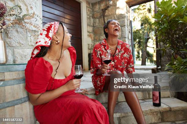 happy female friends laughing on steps - rode jurk stockfoto's en -beelden