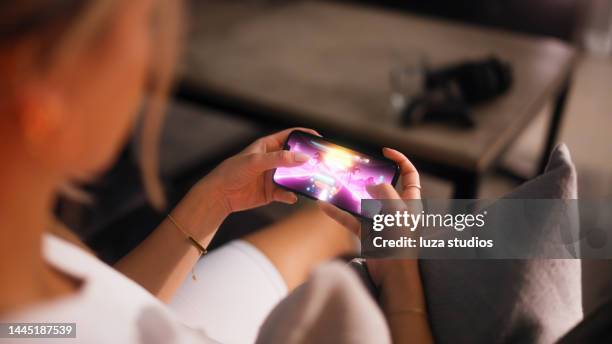 woman playing a mobile racing game on a smartphone - mobile game stock pictures, royalty-free photos & images