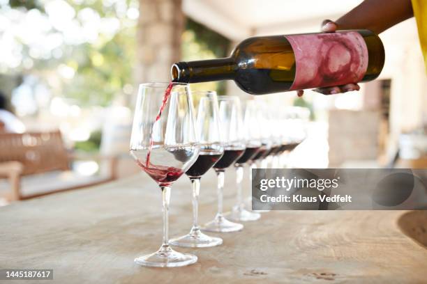 hand of female owner pouring red wine - sommelier stockfoto's en -beelden