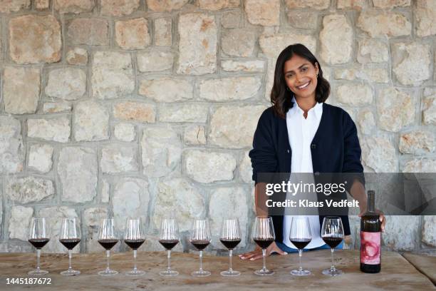 smiling female owner with red wine in winery - sommelier stockfoto's en -beelden
