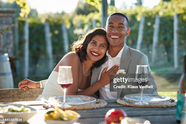 smiling bride leaning on young groom at table - hochzeitspaar stock-fotos und bilder