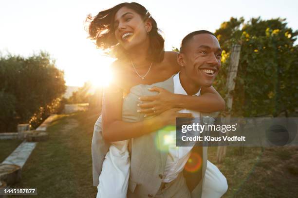 happy man giving piggyback ride to bride in farm - just married stock pictures, royalty-free photos & images