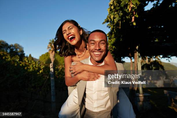 happy groom piggybacking bride in vineyard - couple stock pictures, royalty-free photos & images