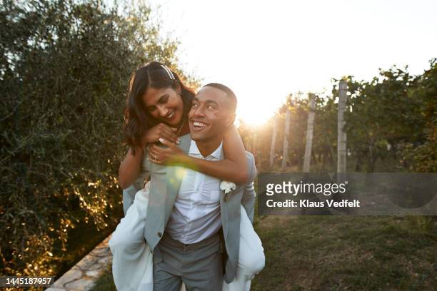 happy man giving piggyback ride to bride - europe bride stock pictures, royalty-free photos & images