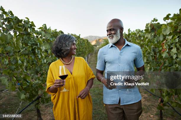 smiling heterosexual couple walking with red wine - montenegro vineyard stock pictures, royalty-free photos & images