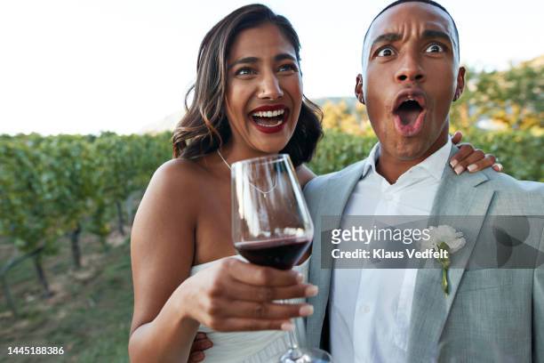 shocked groom and happy bride holding wineglass - wedding couple laughing photos et images de collection